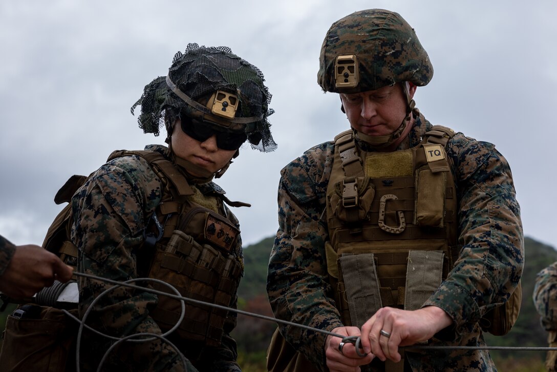 U.S. Marine Corps Sgt. Danielle Cristobal, left, and Col. Peter B. Eltringham tie into the mainline of detonating cord during a demolition range at the Central Training Area, Camp Hansen, Okinawa, Japan, on Jan. 25, 2025. On a demolition range, Marines practice clearing obstacles, establishing defenses and creating pathways to simulate real world scenarios. Cristobal, a native of Michigan, is a combat engineer with 12th Littoral Logistics Battalion, 12th Marine Littoral Regiment, 3d Marine Division. Eltringham, a native of Rhode Island, is the commanding officer of 12th MLR.  (U.S. Marine Corps photo by Lance Cpl. Rodney Frye)