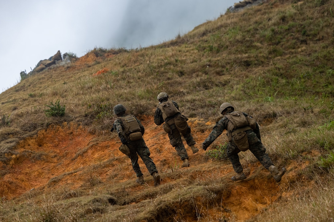 U.S. Marines advance towards the top of a hill during a live-fire squad attack on Camp Schwab, Okinawa, Japan, March 13, 2025. Squad-level live-fire training strengthens combat readiness by sharpening the skills and cohesion of Marine Corps rifle squads. This training enhances tactical proficiency while fostering small-unit leadership and decision-making under realistic conditions. The Marines are with 12th Littoral Combat Team, 12th Marine Littoral Regiment, 3d Marine Division. (U.S. Marine Corps photo by Cpl. John Simpson)