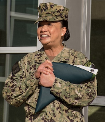 Capt. Maria Edusada, outgoing director of Navy Medicine Readiness Training Command Bremerton’s Directorate of Administration, expresses her thanks to assemble staff members upon receiving a folded directorate for administration flag during a surprise ceremony, May 6, 2025.  (Official Navy photo by Mass Communication Specialist 2nd Class Jennifer Benedict, NHB/NMRTC Bremerton public affairs).