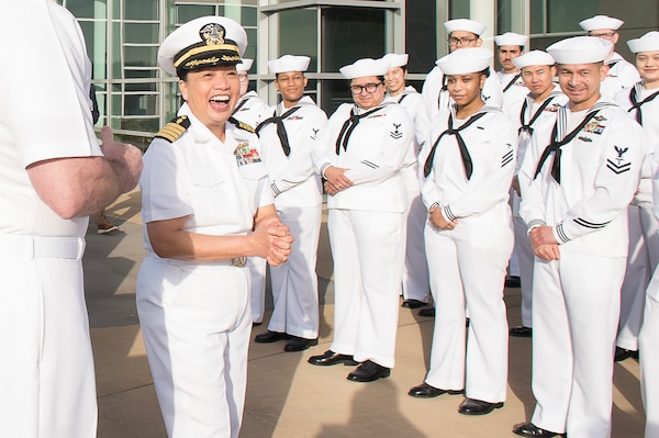 Capt. Maria Edusada, outgoing director of Navy Medicine Readiness Training Command Bremerton’s Directorate of Administration, is surprised during her final directorate uniform inspection by being presented her DFA guidon, customized and framed, May 8, 2025. Master Chief Hospital Corpsman Joshua Akins explained “on behalf of your entire directorate, this is just a small token of appreciation. With added flair.”  (Official Navy photo by Mass Communication Specialist 2nd Class Jennifer Benedict, NHB/NMRTC Bremerton public affairs).