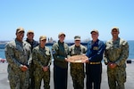 U.S. Navy Lt. Cmdr. Mayra Monarrez, Casualty Receiving Transport Ship 2's officer in charge, middle, receives a plaque from Cmdr. Kayleigh Kirk, USS Tripoli's (LHA 7) Senior Medical Officer, middle left, and Senior Chief Hospital Corpsman Nickolas Westberg, Tripoli's medical senior enlisted leader, while conducting Amphibious Familiarization Training, May 7, 2025. Shipboard familiarization increases operational readiness within the Pacific Fleet and expedtionary medicine worldwide. The mission of NMCSD is to provide a superior experience for our patients, staff, and warfighters. NMCSD employs more than 5,000 active-duty military personnel, civilians, and contractors in southern California to deliver exceptional care afloat and ashore. (U.S. Navy photo by Mass Communication Specialist 2nd Class Jacob Woitzel)