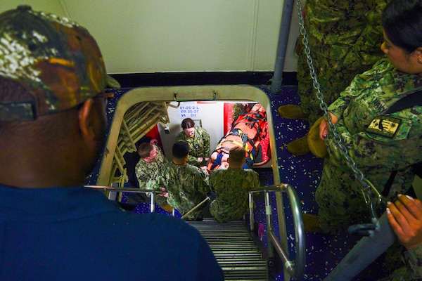 U.S. Navy Sailors assigned to Casualty Receiving Transport Ship 2 and CRTS-6 from Navy Medicine Readiness and Training Command San Diego transport a mock patient through a ladderwell aboard USS Tripoli (LHA 7) while conducting Amphibious Familiarization Training, May 7, 2025. Shipboard familiarization increases operational readiness within the Pacific Fleet and expedtionary medicine worldwide. The mission of NMCSD is to provide a superior experience for our patients, staff, and warfighters. NMCSD employs more than 5,000 active-duty military personnel, civilians, and contractors in southern California to deliver exceptional care afloat and ashore. (U.S. Navy photo by Mass Communication Specialist 2nd Class Jacob Woitzel)