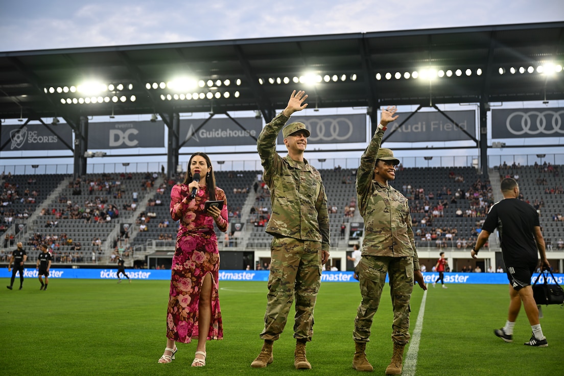 U.S. Air Force Col. Ryan A.F. Crowley, center, commander of Joint Base Anacostia-Bolling and the 11th Wing, and Chief Master Sgt. Catrell Wilson, right, senior enlisted leader of the 11th Operations Group, wave to attendees and veterans during a DC United Football Club match at Audi Field in Washington D.C., May 3, 2025. Haiya Kofler, Left, football host, introduced Crowley and Wilson during DC Military Appreciation Night. (U.S. Air Force photo by Staff Sgt. Brandon Schneider)