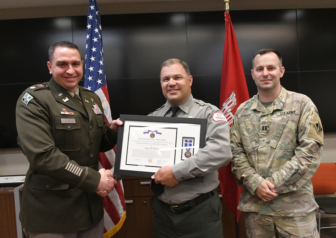 Lt. Col. Robert Green, U.S. Army Corps of Engineers Nashville District commander, left, presents the Department of the Army Civilian Service Achievement Medal to Conservation Biologist Gary Bruce of Center Hill Lake as Capt. Matthew Gursky, right, looks on May 5, 2025, in Nashville, Tenn. Bruce was recognized for nearly two decades of volunteer training service, enhancing the safety and readiness of Corps rangers. (USACE Photo by Noe Gonzalez)