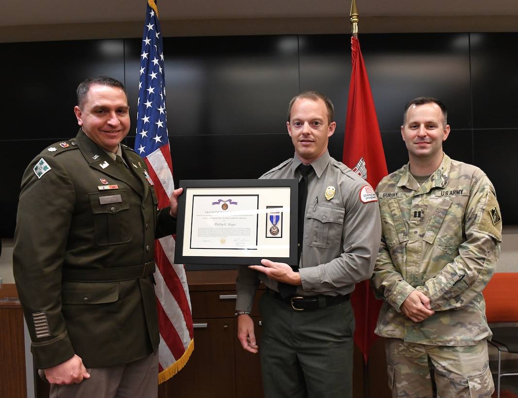 Lt. Col. Robert Green, U.S. Army Corps of Engineers Nashville District commander, left, presents the Department of the Army Civilian Service Achievement Medal to Natural Resources Specialist Phillip Sliger of Center Hill Lake as Capt. Matthew Gursky, right, looks on May 5, 2025, in Nashville, Tenn. Sliger was honored for leading ranger safety training and defensive tactics instruction across the district and division. (USACE Photo by Noe Gonzalez)
