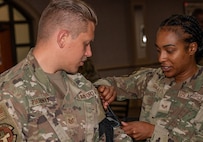 One white male Airman allows a black female Airman to practice applying a tourniquet during a medical exercise.