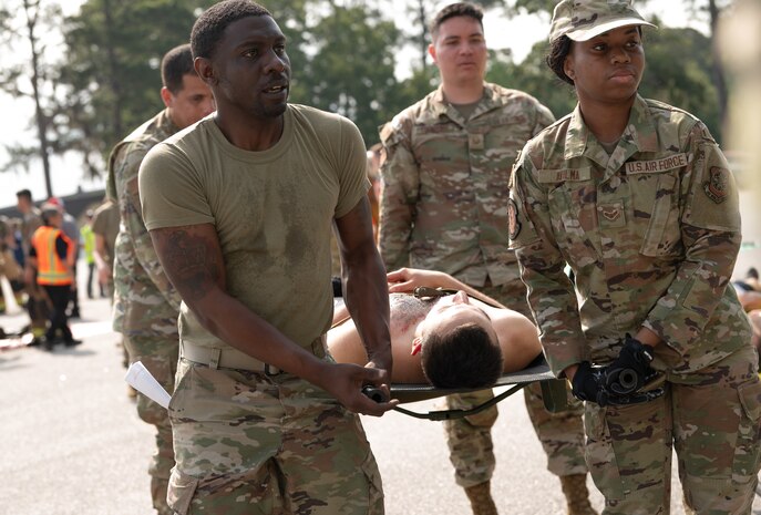 Airmen carry a man on a litter during a medical exercise.