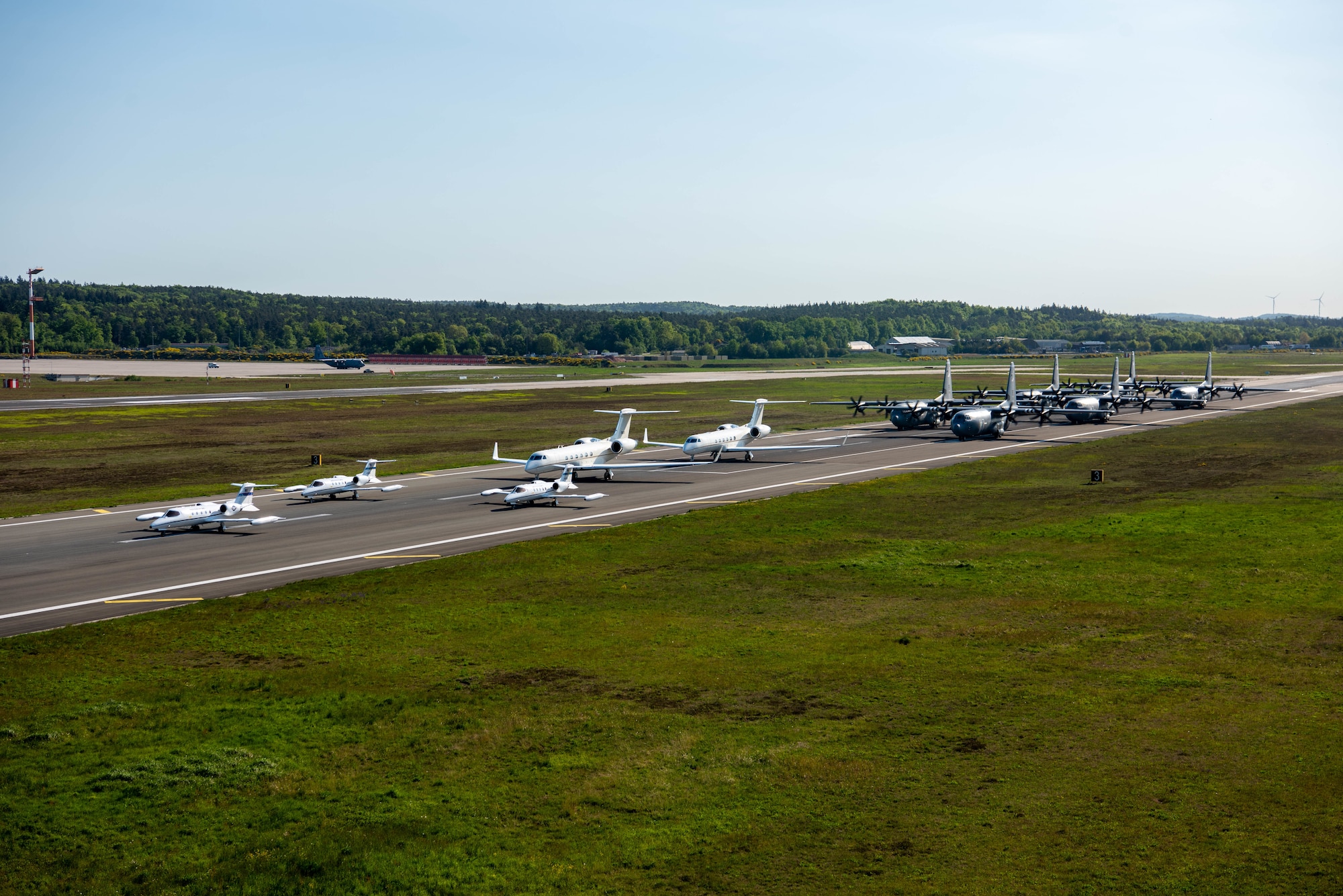 Three C-21A Learjet, two C-37A Gulfstream and six C-130J Super Hercules aircraft sit in a formation on the flightline