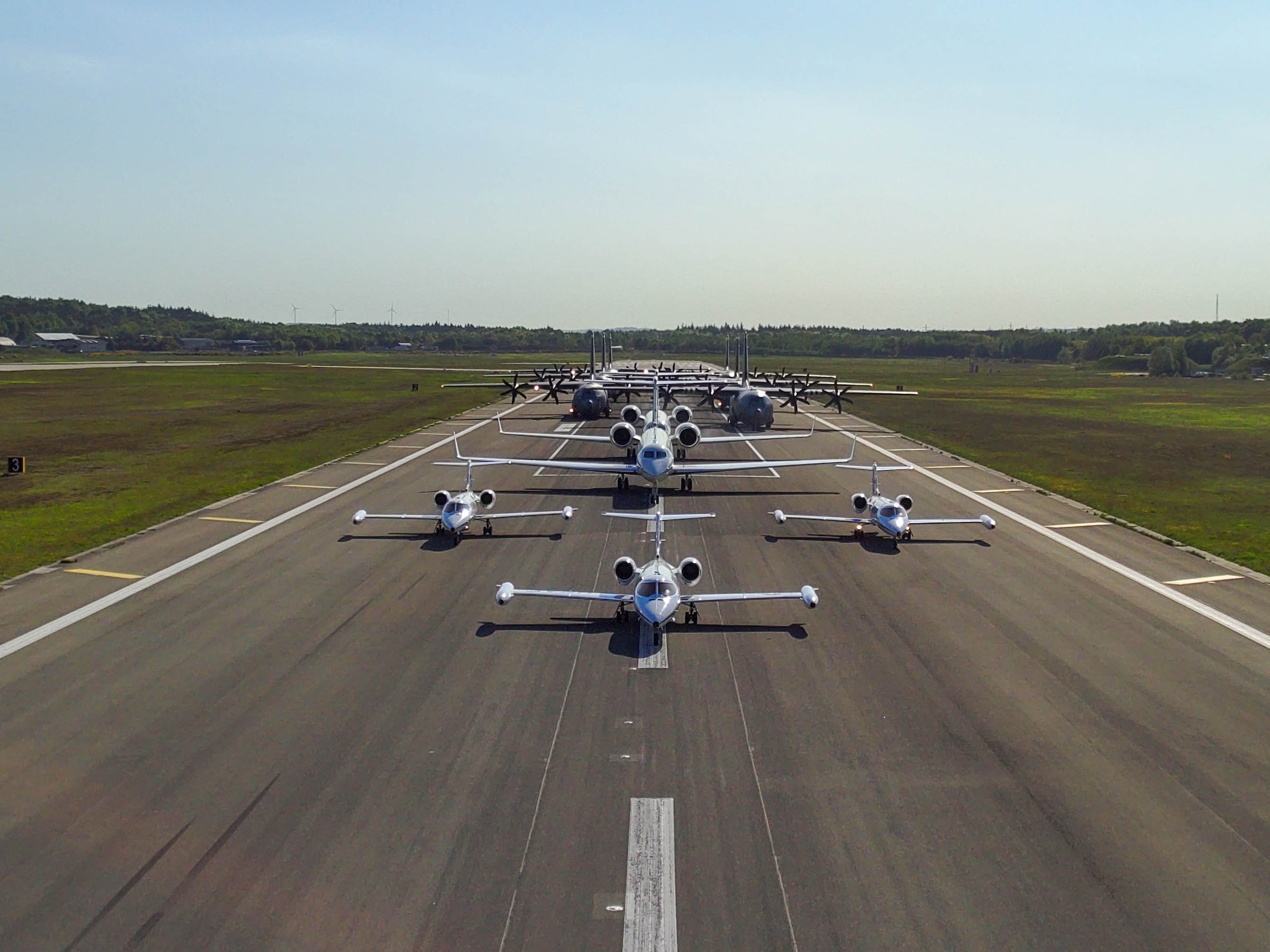 three C-21A Learjet, two C-37A Gulfstream and six C-130J Super Hercules aircraft sit in a formation on the flightline