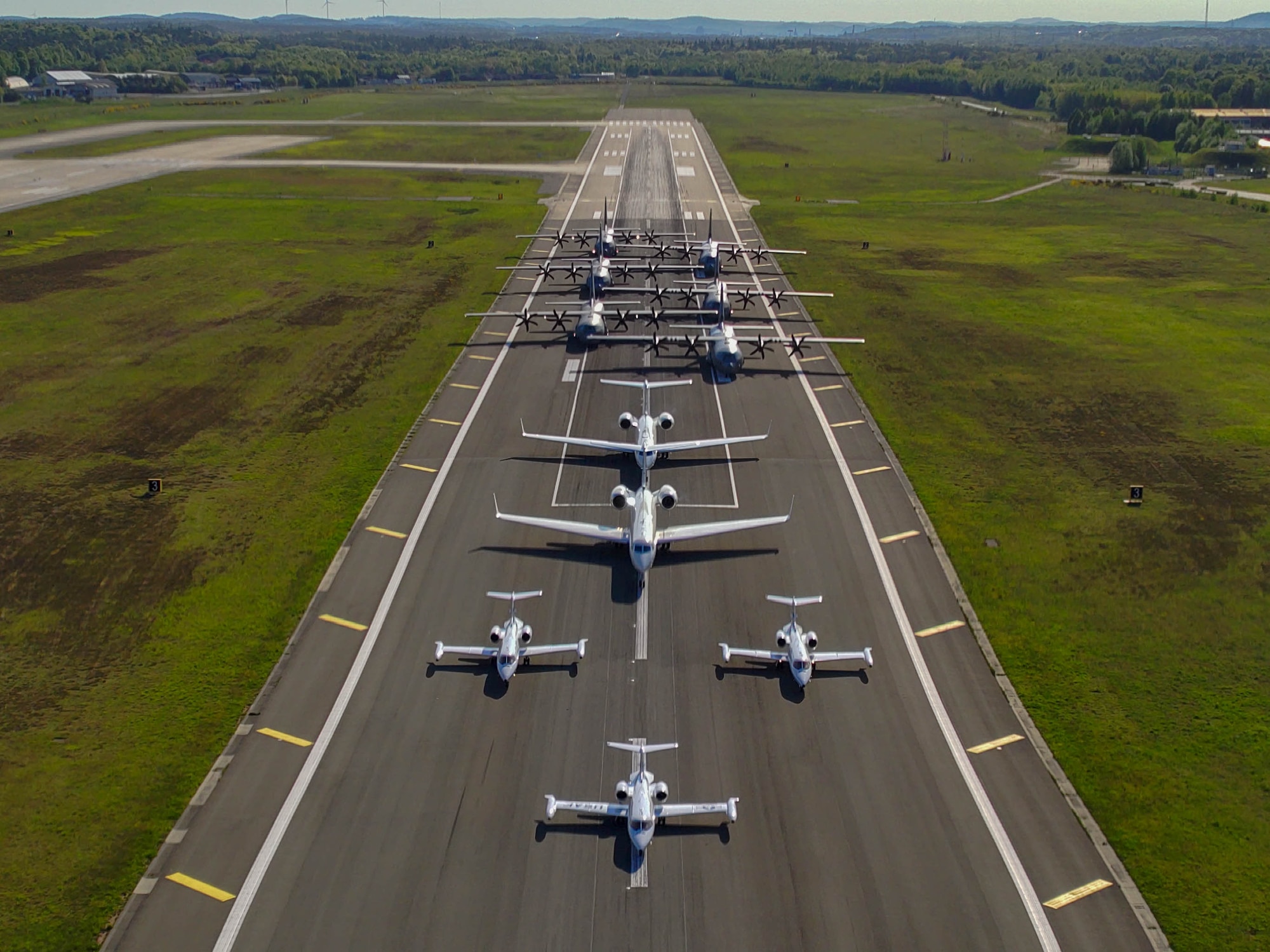 three C-21A Learjet, two C-37A Gulfstream and six C-130J Super Hercules aircraft sit in a formation on the flightline