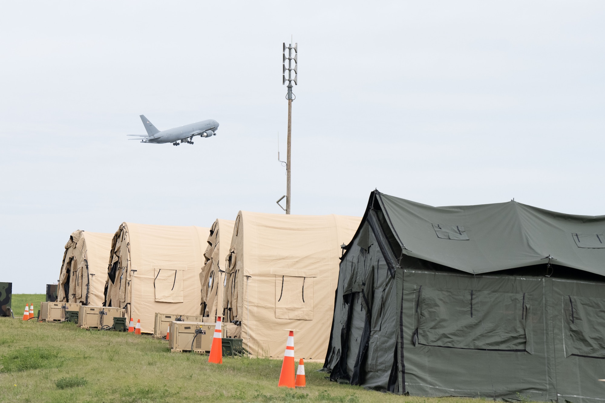 A KC-46A Pegasus takes off over tent city during exercise Lethal Stack at McConnell Air Force Base, Kansas, May 6, 2025. The weeklong exercise tested units’ ability to deploy, generate aircraft and operate within a contested environment. (U.S. Air Force photo by Senior Airman Felicia Przydzial)