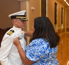 Capt. Martin Braud, EMF-Kilo commanding officer, is pinned as the acting commander by his wife during the Expeditionary Medical Facility Kilo change of command ceremony at Marston Pavillion, on May 9, 2025. EMF-Kilo is the readiness platform attached to Navy Medicine Readiness and Training Command Camp Lejeune and is comprised of approximately 400 personnel ready to deploy field hospital capabilities during humanitarian or combat mission.