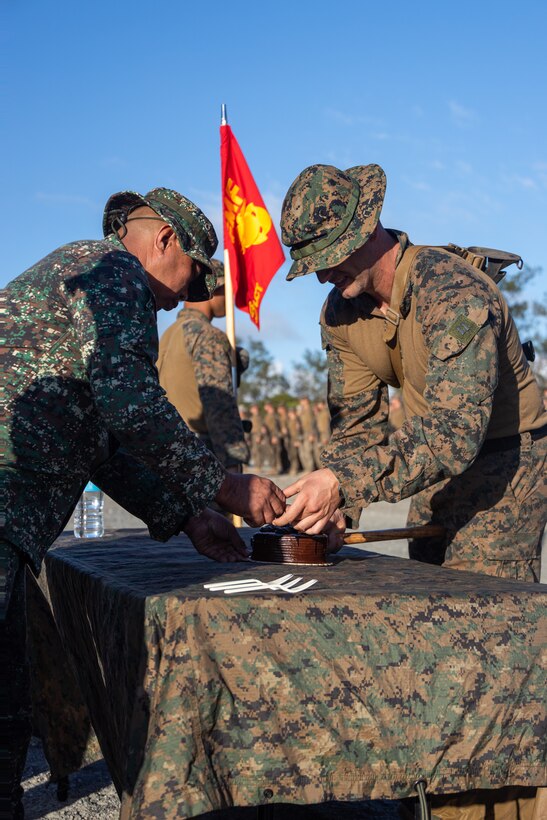 U.S. Marine Corps Capt. Stephen Knego, commanding officer of Ares Company, 3d Littoral Combat Team, 3d Marine Littoral Regiment, 3d Marine Division, hands a Philippine Marine with the Coastal Defense Regiment, a piece of cake as part of a ceremony during KAMANDAG 7 at Paredes Air Station, Philippines, Nov. 10, 2023. KAMANDAG is an annual Philippine Marine Corps and U.S. Marine Corps-led exercise aimed at improving multinational readiness, relationships, and mutual capabilities in the advancement of a Free and Open Indo-Pacific. This year marks the seventh iteration of this exercise and includes participants from Japan, the Republic of Korea, and observers from the United Kingdom. The ceremony celebrated the 248th birthday of the U.S. Marine Corps and included service members from the Philippine Marine Corps, 3d MLR, and 3d Marine Logistics Group. (U.S. Marine Corps photo by Sgt. Jacqueline C. Parsons)