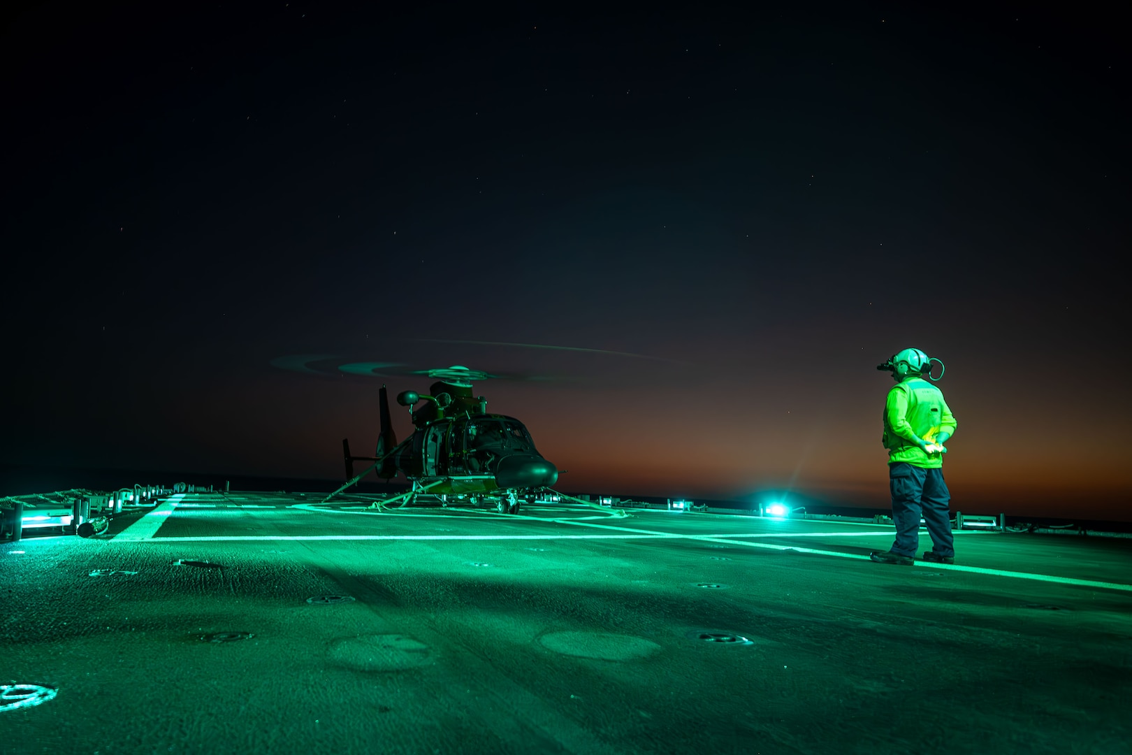 Ensign Wyatt Rumpf, a landing safety officer aboard the U.S. Coast Guard Cutter Kimball (WMSL 756), oversees an MH-65 Dolphin Helicopter Interdiction Tactical Squadron aircrew preparing to conduct night flight operations while Kimball patrols the Eastern Pacific Ocean, March 6, 2025. From the U.S. Western States to the Indo-Pacific, and from the Arctic to Antarctica, U.S. Coast Guard Pacific Area cutters and personnel protect the maritime borders, territorial integrity, and sovereignty to promote a safer, stronger, and more prosperous America.