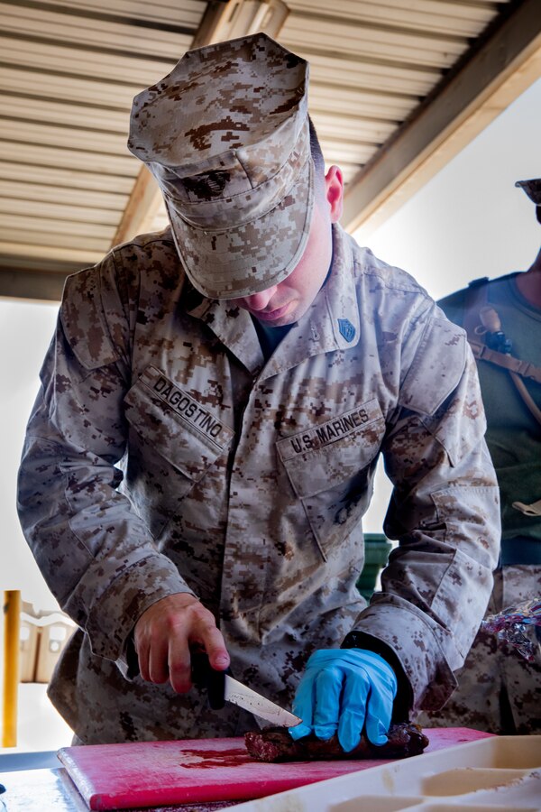 U.S. Marine Corps Gunnery Sgt. Taylor J. Dagostino, mess management chief, Headquarters Company, 23rd Marine Regiment, 4th Marine Division, prepares food for the warrior meal at Integrated Training Exercise 4-24, Marine Corps Air-Ground Combat Center, Twentynine Palms, California, June 23, 2024. Active and reserve component integration is vital to sharing knowledge and demonstrating how the two support each other. Reserve Marines and Sailors have come together from across the nation to form an integrated Marine Air-Ground Task Force to take part in a live-fire, combined arms exercise that will better prepare Marine Forces Reserve in its mission to augment and reinforce the active component. (U.S. Marine Corps photo by Orion Stpierre)