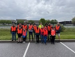 A group of people in reflective safety vests pose for group photo outside.