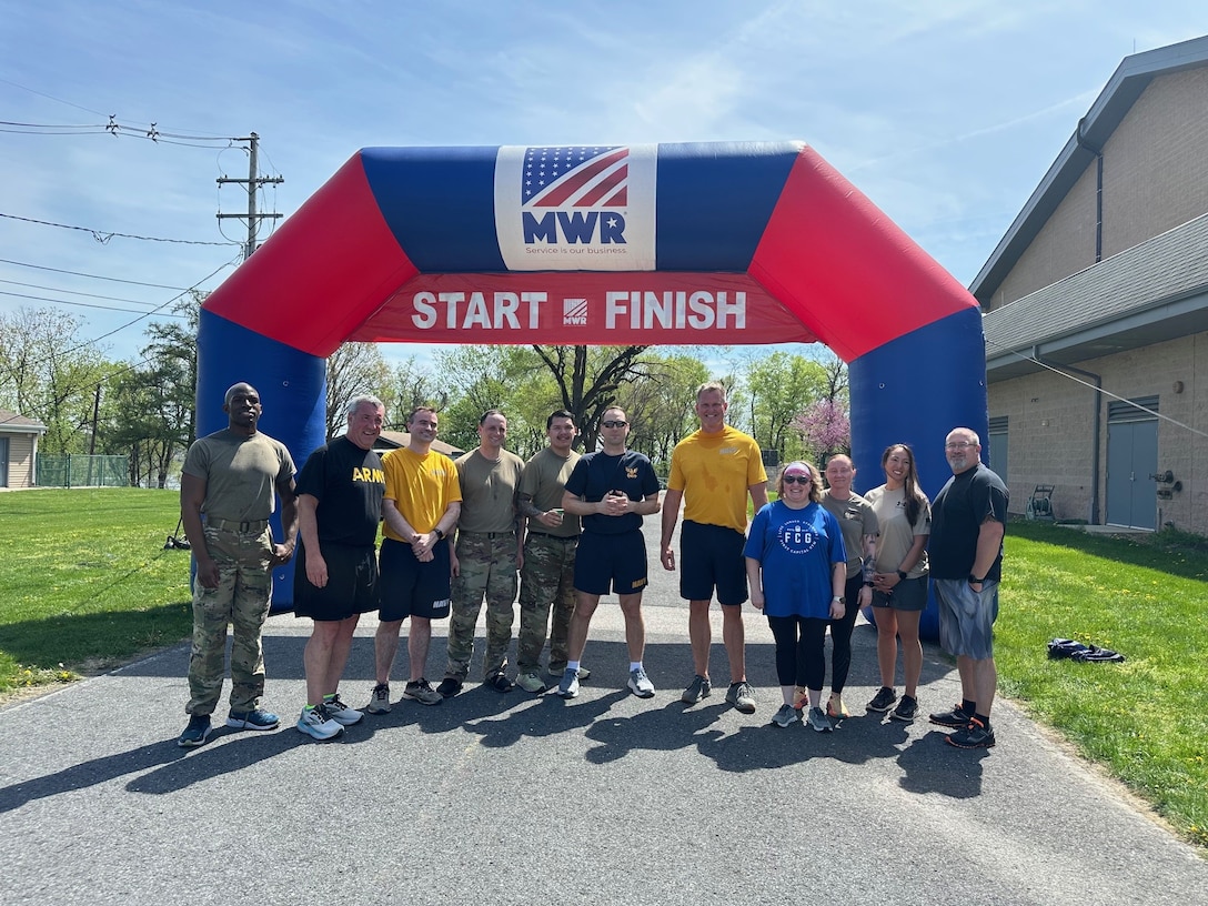 A group of people stand outside under an inflatable race start & finish banner.