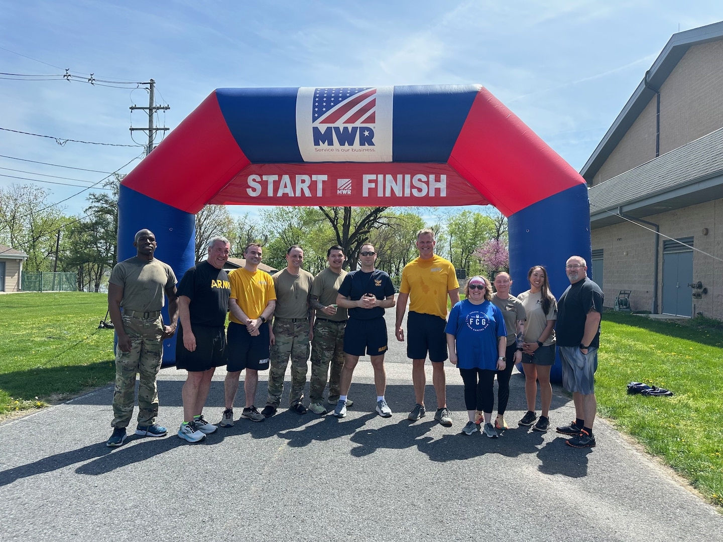 A group of people stand outside under an inflatable race start & finish banner.