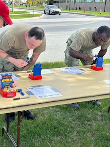 Two Service Members look at items on a table.