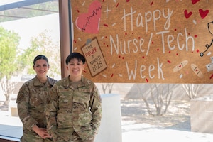 U.S. Air Force Capt. Michelle Maciocha, 355th Medical Group registered nurse and family health officer in charge, left, and Airman 1st Class Kaisy Cochrane, 355th MDG aerospace medical technician, right, pose by a Nurse and Technician Appreciation Week poster at Davis-Monthan Air Force Base, Arizona, May 7, 2025. Maciocha and Cochrane go above and beyond to provide the Desert Lightning Team with the highest level of care. (U.S. Air Force photo by Airman Jaden Kidd)
