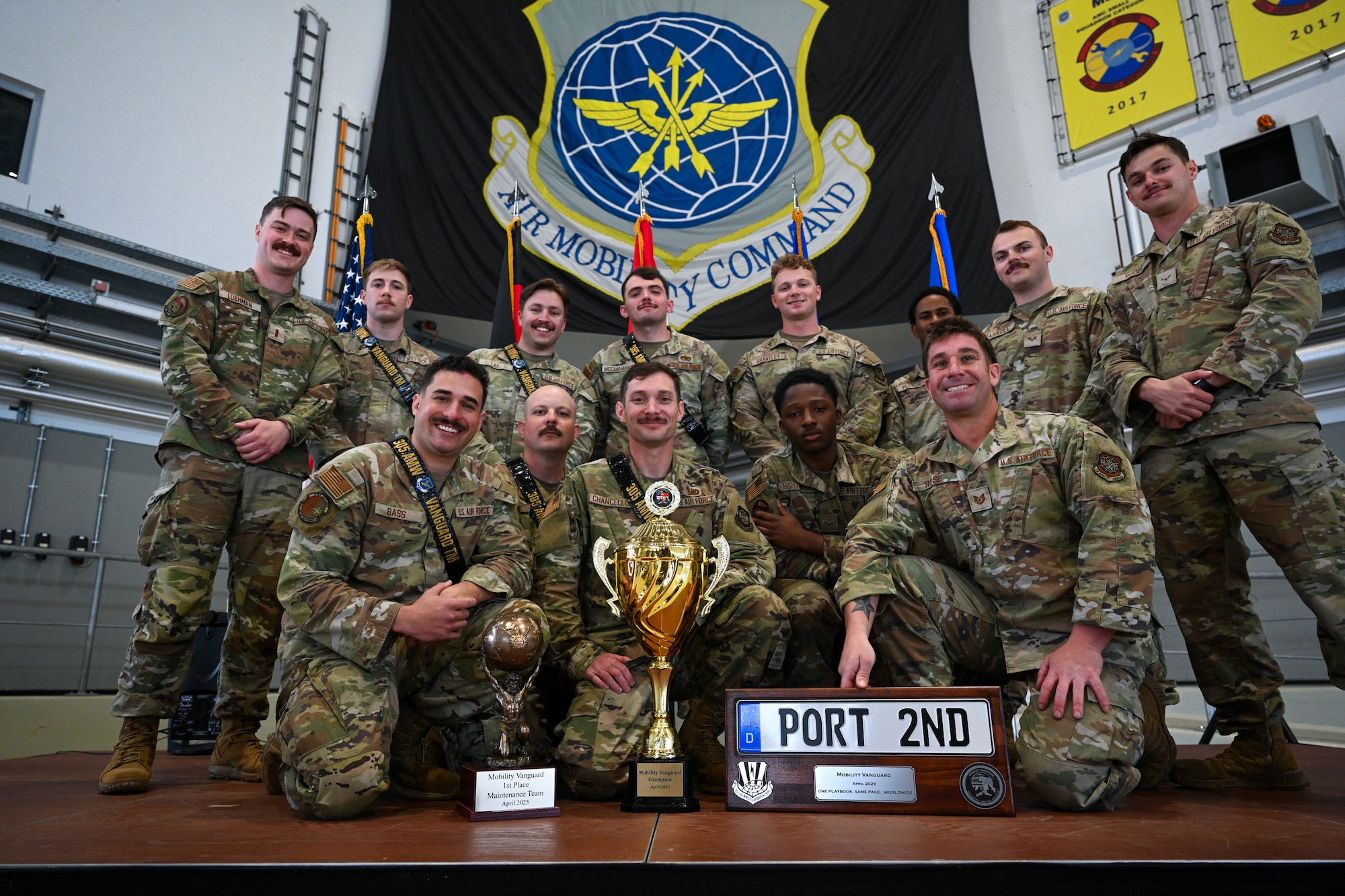 U.S. Air Force Airmen of the 305th Air Mobility Wing (AMW), headquartered at Joint Base McGuire-Dix-Lakehurst, N.J., pose with their awards for taking top honors at the 521st Air Mobility Operations Wing’s Mobility Vanguard 2025 at Ramstein Air Base, Germany, April 25, 2025. Two teams from the 305th AMW— one from the 305th Aircraft Maintenance Squadron (AMXS) and the other from the 305th Aerial Port Squadron (APS) — competed in the strategic evaluation that included several grueling challenges for 22 military aerial port and maintenance teams from across the U.S. Air Force, Germany, and the Netherlands, with a focus on daily mobility aircraft generation. The 305th AMXS team emerged as the top overall performers, securing first place in both the overall and maintenance categories. The 305th APS team finished second place in both the overall and port categories. (U.S. Air Force photo by Staff Sgt. Joshua T. Crossman)