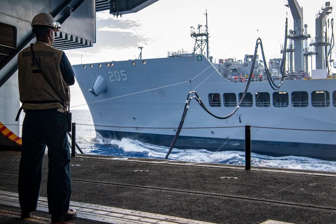 Capt. Justin Eckhoff, executive officer of the aircraft carrier USS Nimitz (CVN 68), observes a replenishment-at-sea with the fleet replenishment oiler USNS John Lewis (T-AO 205) from the hangar bay of the aircraft carrier USS Nimitz (CVN 68) in the South China Sea, May 5, 2025.