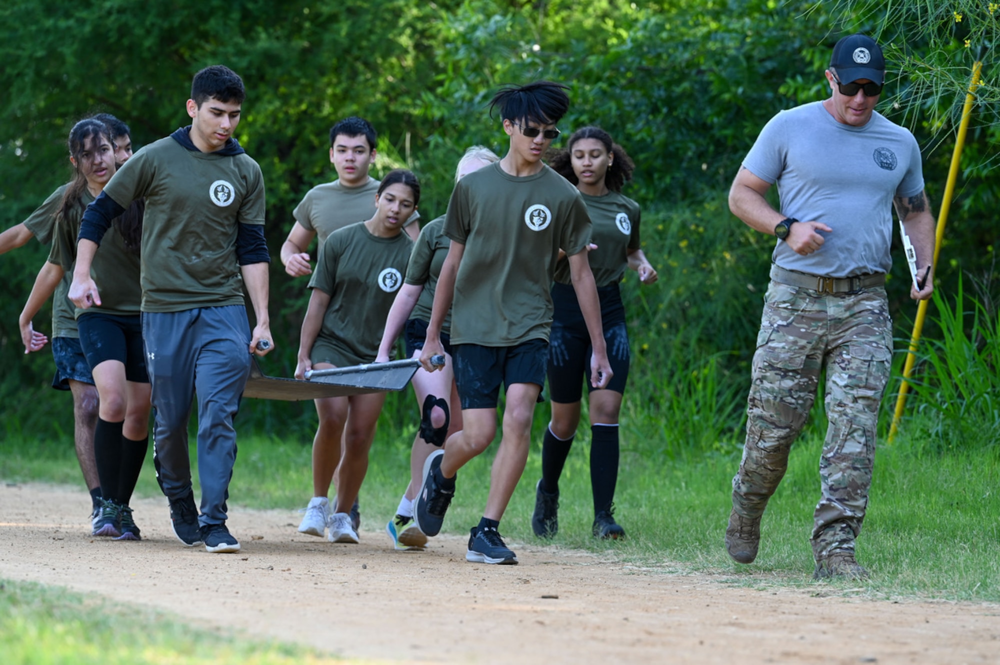 eight students running with litter and military mentor