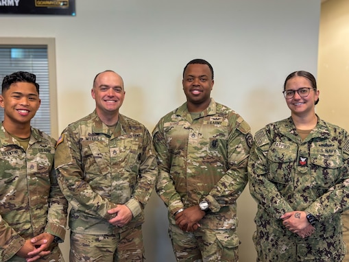 Four recruiters standing together at a recruiting station.