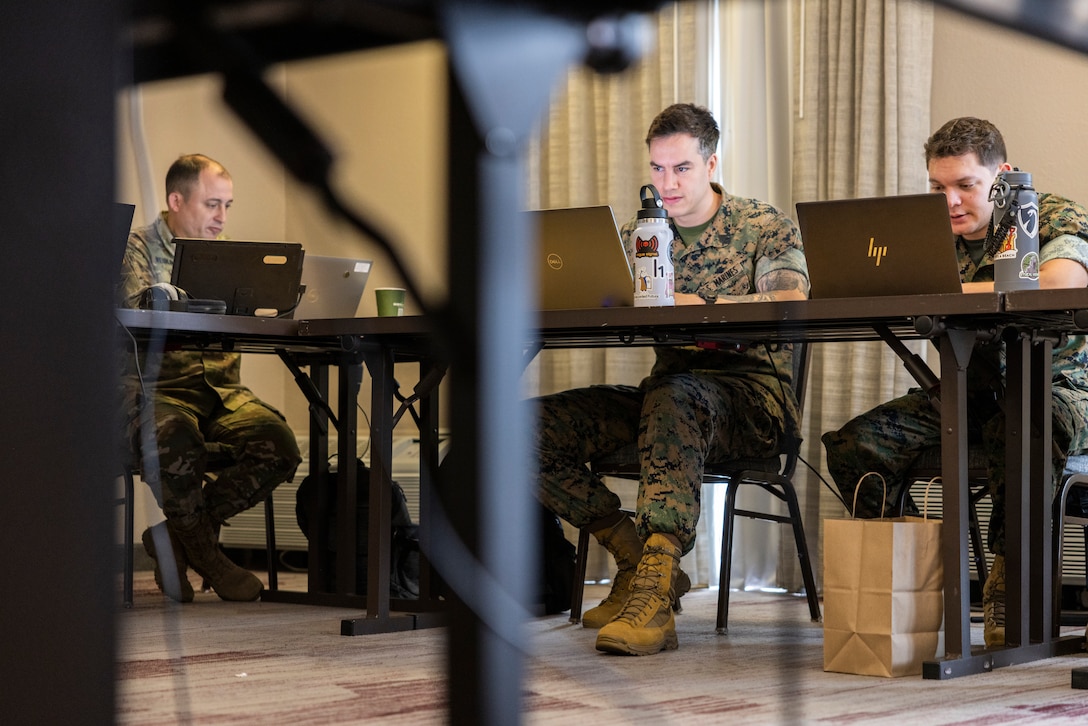U.S. Army Lt. Col. Brian Weiblinger, left, team chief, Defense of Cyber Operations Element Team, Florida Army National Guard, and U.S. Marine Corps Sgt. Thane Murphy, center, intelligence analyst, and Sgt. Victor Navarro, right, cyber warfare operator, Defensive Cyberspace Operations Internal Defensive Measures, conduct defensive cyber operations during exercise Southern Defender 25 in Augusta, Georgia, May 6, 2025. This exercise pushes teams to identify vulnerabilities, respond to adversary injects, and coordinate actions across 28 teams in 15 locations consisting of 20 participating countries in real time. (U.S. Marine Corps photo by Sgt. Samuel Qin)
