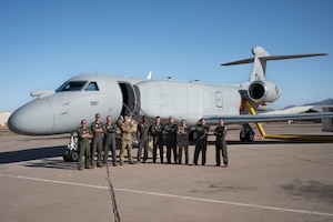 U.S. Airmen assigned to the 43rd Electronic Combat Squadron pose for a group photo before boarding the EA-37B Compass Call aircraft for its first official mission training sortie flight at Davis-Monthan Air Force Base, Arizona, May 2, 2025. The EA-37B sustains Joint Force military advantage in the electromagnetic battlespace and builds a more lethal force by modernizing electromagnetic attack capabilities to deny peer competitors' tactical networks and information ecosystems. (U.S. Air Force photo by Airman Samantha Melecio)