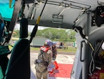 Members of an MH-65 Dolphin helicopter crew from Coast Guard Air Station Barbers Point carry an ailing fishing vessel captain on the landing pad at Hilo Medical Center in Hilo, Hawaii, May 9, 2025. The crew hoisted the man from the fishing vessel Sea Angel 80 miles offshore Hilo. (U.S. Coast Guard photo, courtesy Air Station Barbers Point)