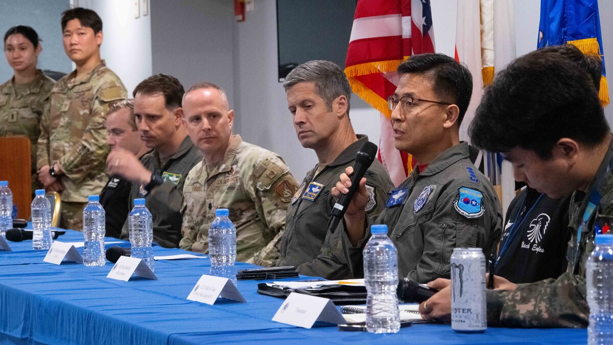 military members sitting at a table with one on the microphone