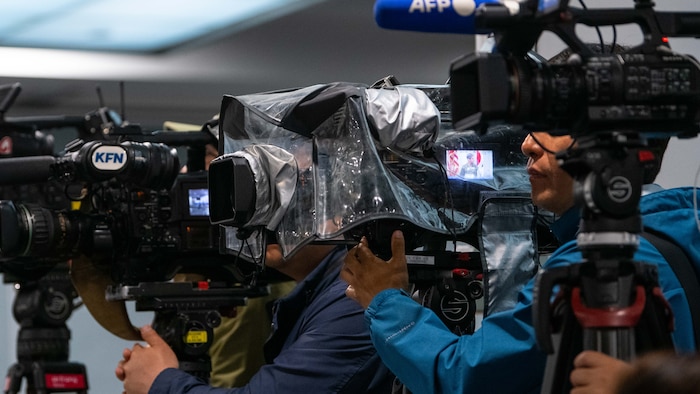 a tightly framed photo of news agency camera men with large video camera mounted on tripods