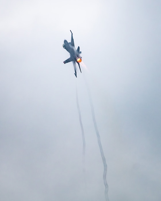 an F-16 fighter jet climbs straight up into the sky