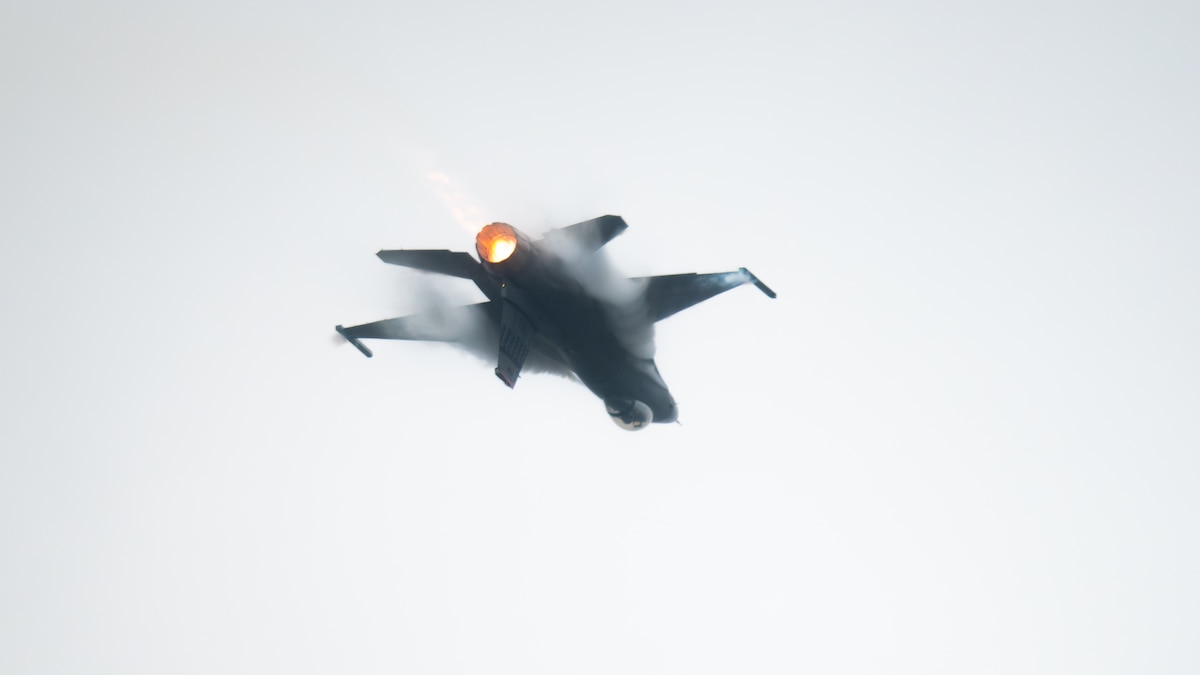 F-16 fighter jet flies inverted through the sky