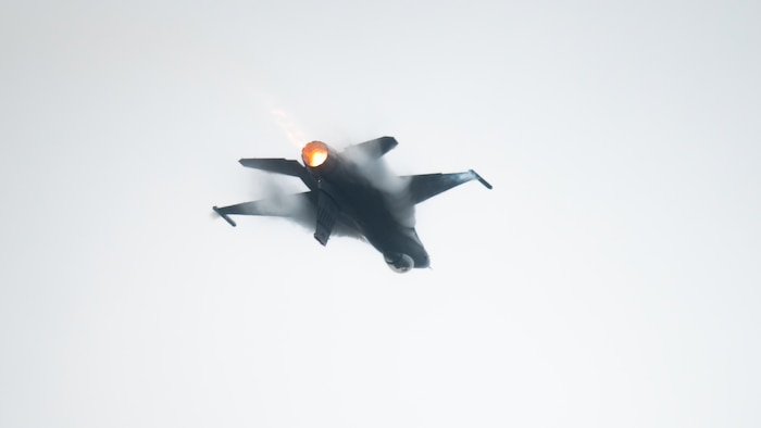F-16 fighter jet flies inverted through the sky
