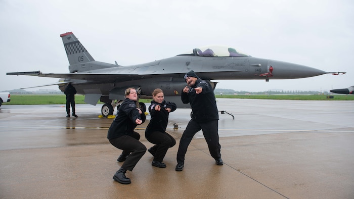 people pose in front of a fighter jet