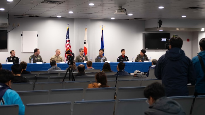 military members sit at a table in an auditorium with media members