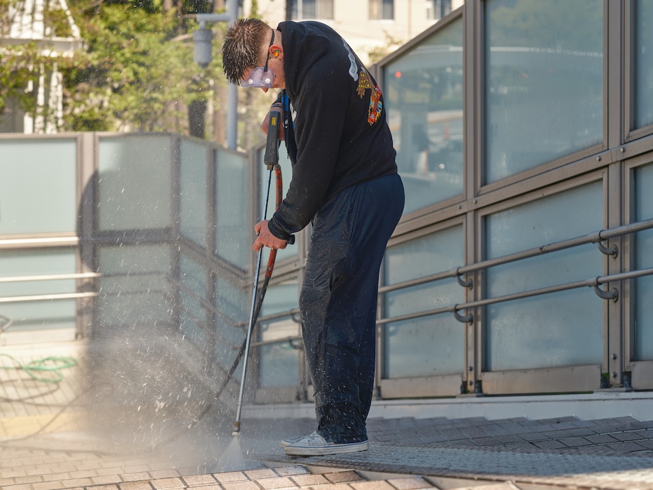 Retail Specialist Seaman Recruit John Kibbe, a USS Blue Ridge (LCC 19) Sailor temporarily assigned to Commander, Fleet Activities Yokosuka Transient Personnel Unit, uses a pressure washer outside the installation's Carney Pedestrian Gate Wednesday, April 16 in Yokosuka, Japan.