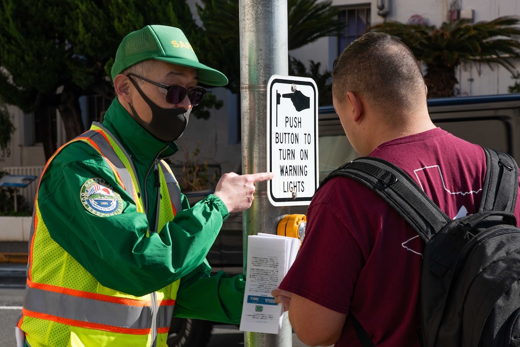 Safety Inspector Akihiro Yoshida, with Safety Department of Commander, Fleet Activities Yokosuka (CFAY), speaks to a pedestrian and ensures that traffic rules are being followed during the street safety campaign onboard Commander, Fleet Activities Yokosuka (CFAY).