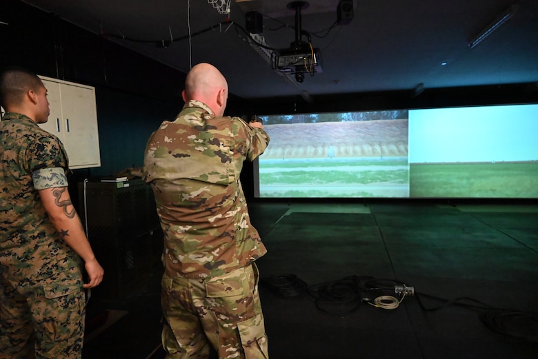 An Airman shoots at a virtual target on a screen.