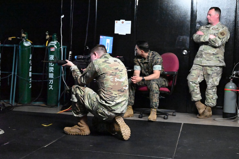 An Airman aims at a virtual target while other servicemembers look on.