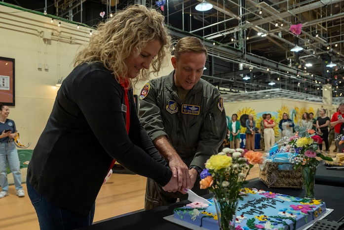 U.S. Air Force Col. Paul Davidson, right, 35th Fighter Wing commander, and an event organizer cut a cake during Spouse Appreciation Day.