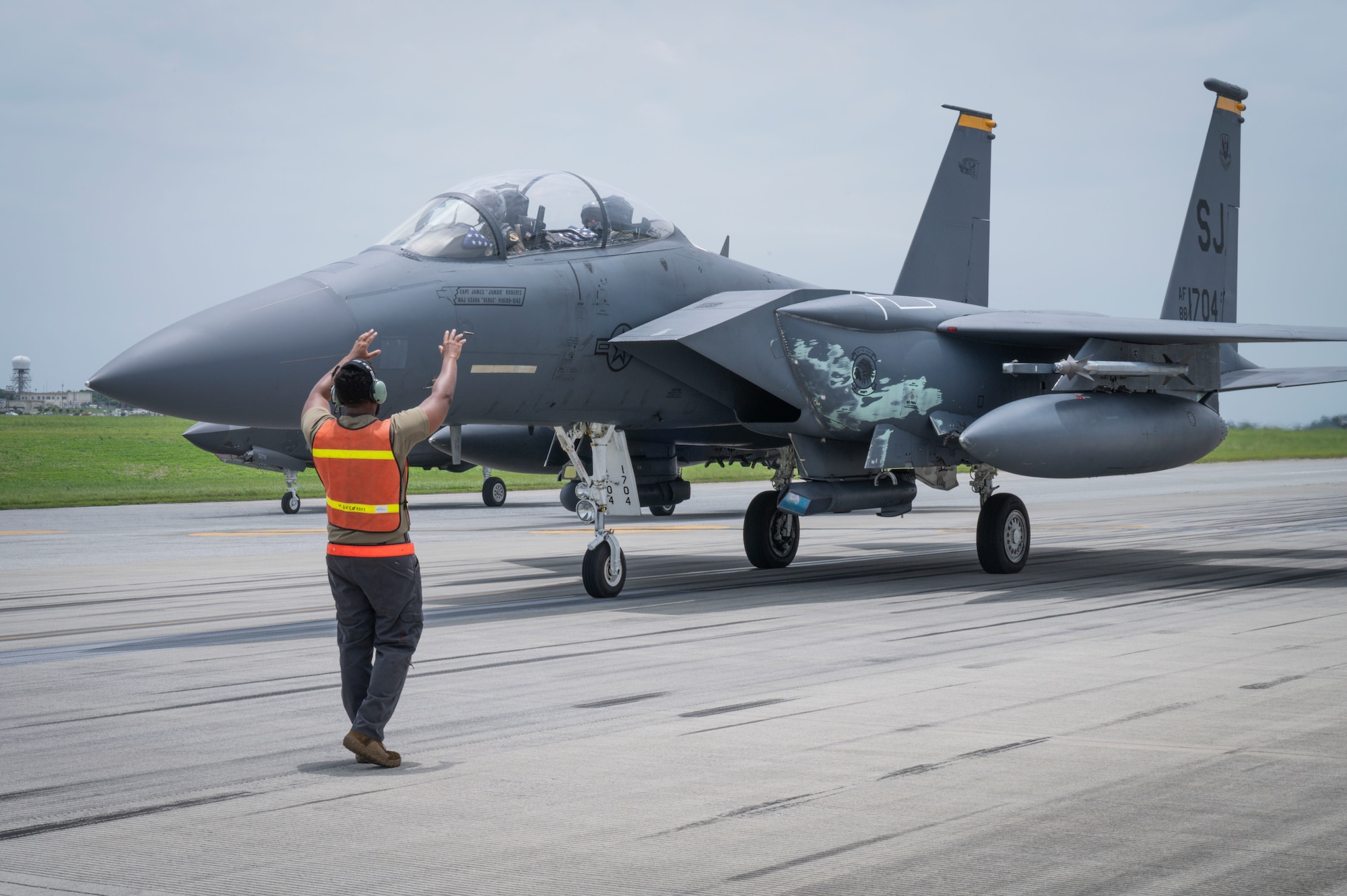 U.S. Air Force Senior Airman Jordan Green, 67th Fighter Generation Squadron crew chief, marshals an F-15E Strike Eagle during an elephant walk at Kadena Air Base