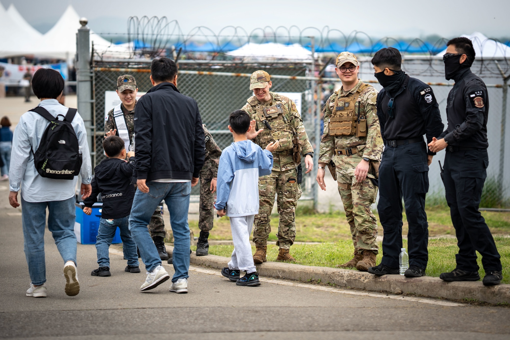 Republic of Korea Air Force and U.S. Air Force 51st Security Forces Squadron personnel welcome visitors at the entrance of Osan Air Power Days 2025 at Osan Air Base, Republic of Korea, May 11, 2025. The joint security presence highlighted the strength of the U.S.-ROK alliance while ensuring the safe arrival of thousands of attendees. (U.S. Air Force photo by Senior Airman Tallon Bratton)