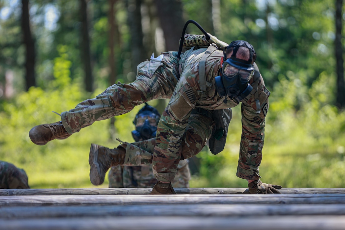 30th Medical Brigade, launches himself over an obstacle during the 21st Theater Sustainment Command Best Squad Competition