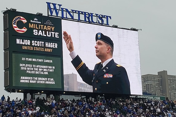 Maj. Scott D. Hager, 85th U.S. Army Reserve Support Command, waves to cheering baseball fans, on the jumbotron, during the Military Salute at the Chicago Cubs Hometown Opener game versus the San Diego Padres on April 4, 2025, at Wrigley Field.