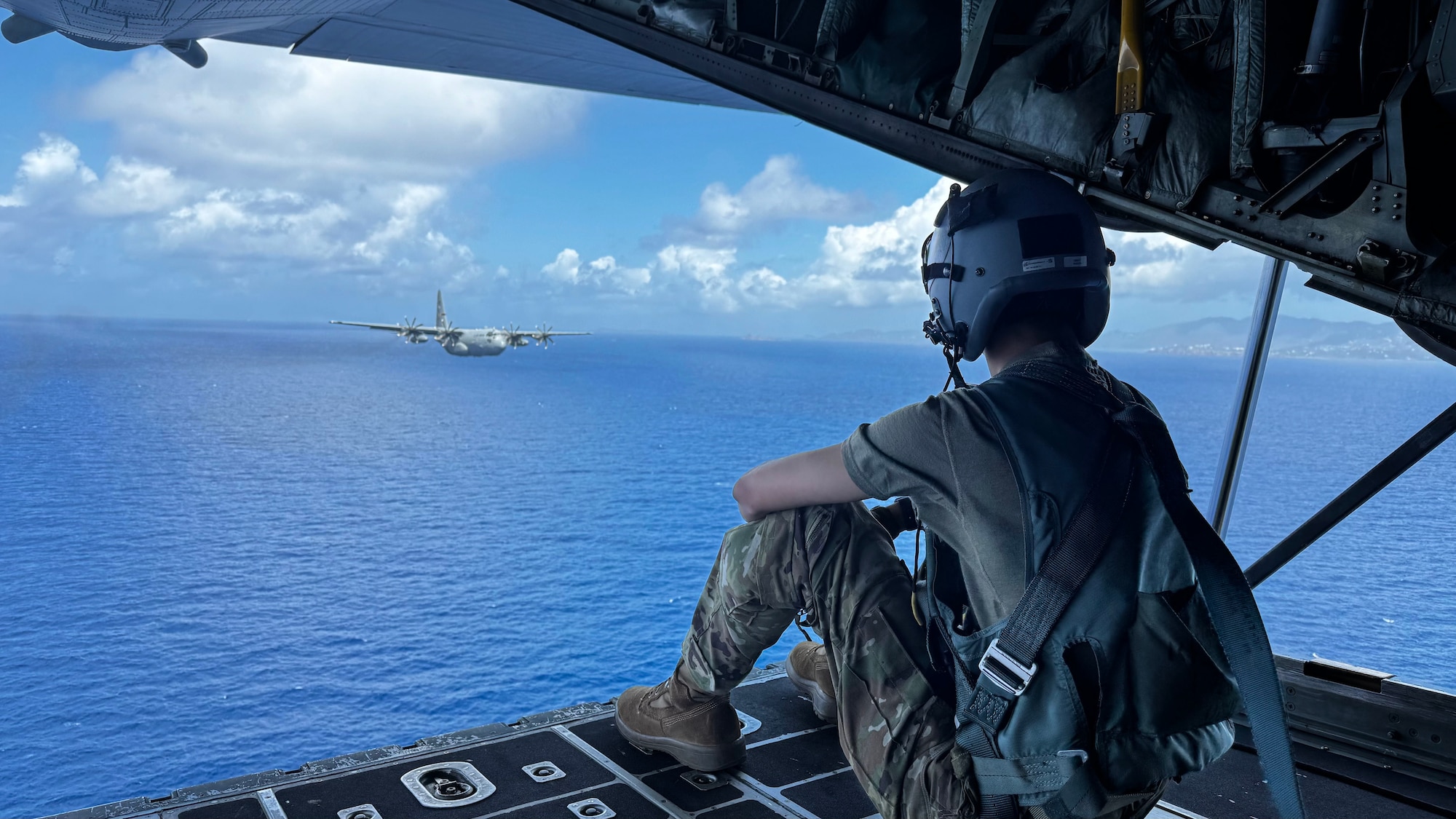 U.S. Air Force Senior Airman Evan Fleischhacker, 109th Airlift Squadron, sits on the ramp of a C-130 Hercules over the waters of St. Croix, U.S. Virgin Islands, April 11, 2025.