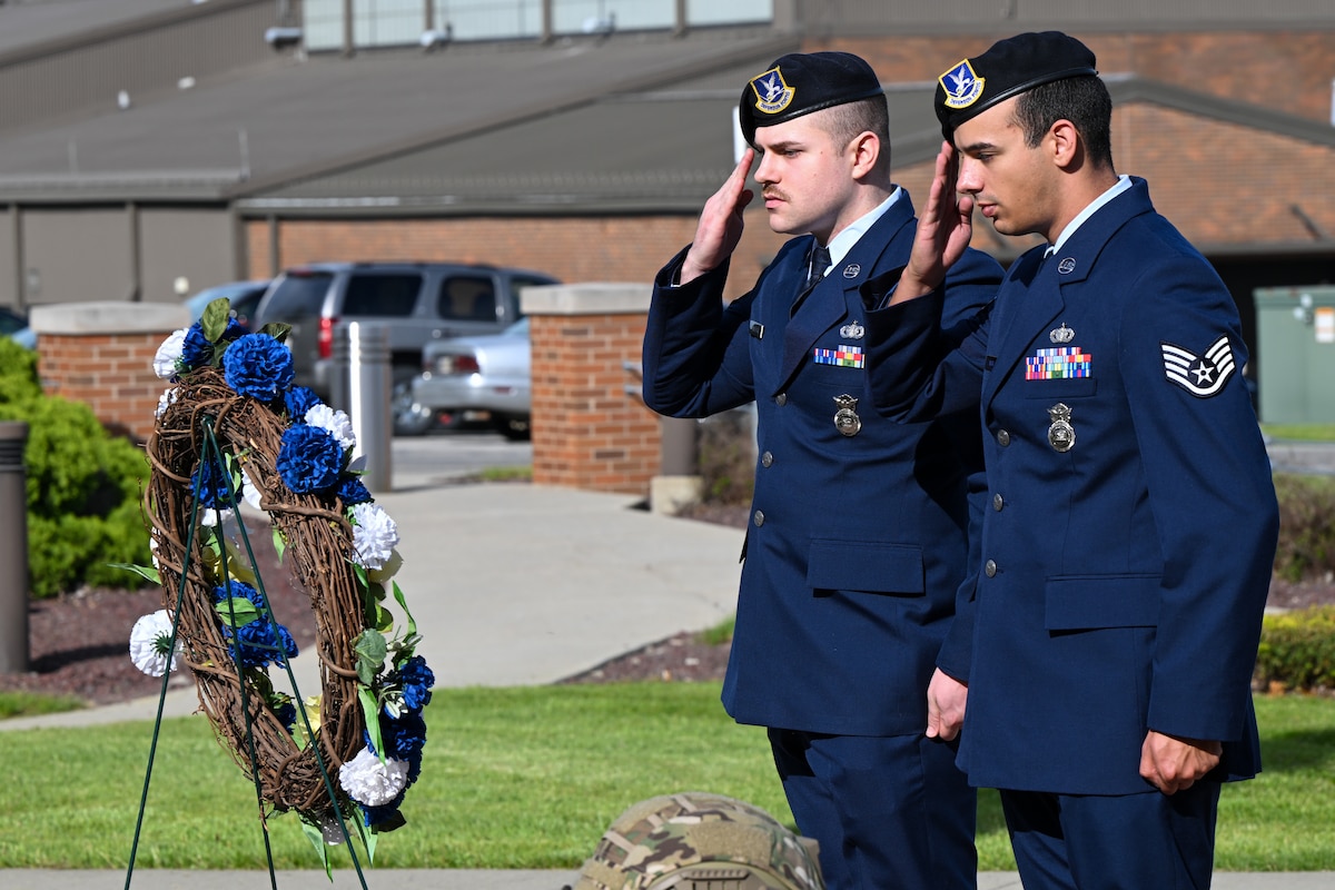 Staff Sgts. Bailey Peachock and Gregory Bass salute a wreath honoring fallen officers during a police officer memorial ceremony to begin National Police Week at Youngstown Air Reserve Station, Ohio, May 11-17, 2025.