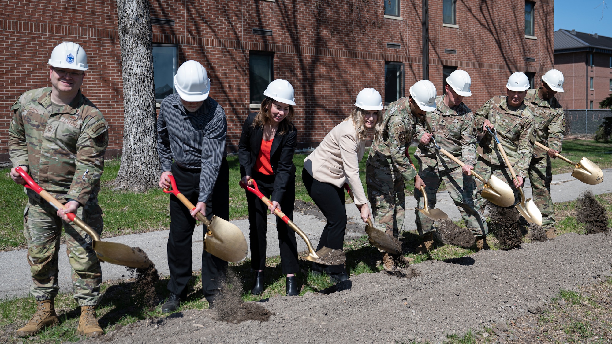 Airmen and civilians assigned to the 319th Reconnaissance Wing, 319th Civil Engineer Squadron and 319th Contracting Squadron break ground during the Bunch Hall dormitory groundbreaking ceremony at Grand Forks Air Force Base, N.D., May 7, 2025. The construction-industry tradition of breaking ground with golden shovels commemorates the start of new construction. (U.S. Air Force photo by Airman Nailah Pacheco)